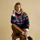 Model seated wearing Charlie Fairisle navy jumper with vibrant fairisle pattern.