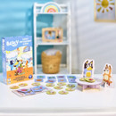 Box of "Bluey Fancy Restaurant Game" on a table with game pieces, depicting playful characters and food items. Background includes shelves and a sunny decor.
