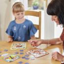 A woman and young girl play an educational board game at a wooden table. The girl smiles, creating a warm and engaging atmosphere.
