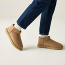 Tan suede ankle boots styled with cream socks and blue jeans while walking, featuring low-profile ridged soles.