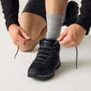 Close-up of a black walking shoe being laced, featuring breathable mesh panels, grey patterned laces and a reinforced toe.
