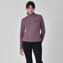 A woman in a mauve long-sleeve, high-neck top and black leggings stands confidently against a neutral background, conveying a calm, stylish tone.