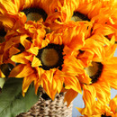 Close-up of bright artificial sunflower heads, showing detailed petals in vivid orange and textured dark centres with a natural-looking finish.