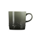 A side view of a green ceramic mug with embossed holly leaves near the bottom and a smooth glossy finish.