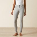 A person wearing light gray, high-waisted leggings and a white top stands barefoot on a wooden floor. The leggings have subtle detailing and a sleek fit.