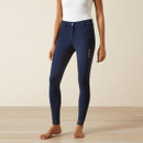 A person in a sleeveless white top and slim-fit, navy riding pants stands barefoot on a light wood floor, conveying a casual and elegant style.