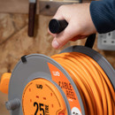 Hand turning non-slip handle on WE 25m cable reel extension lead in workshop