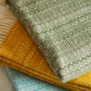 Close up of folded wool blankets in green, yellow and blue.