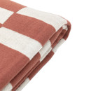 Corner detail of a folded nutmeg throw with a geometric block pattern.