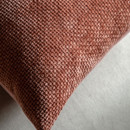 Close-up of a rust cushion showing the woven pattern in detail.