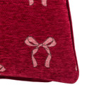 Close-up of the cushion fabric showing an embroidered bow motif with fine stitching detail.