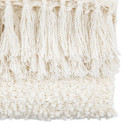 Close-up of the tassel fringe on the natural-coloured throw, showing the woven detail.