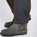 Close-up of a person wearing dark olive trousers with a blue lateral stripe and black boots, standing on a white background, conveying a rugged, outdoor vibe.