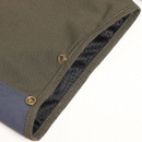 Close-up of a khaki fabric with metal eyelets and blue panel, revealing a black mesh lining. The texture and stitching suggest rugged durability.