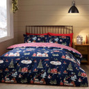 A cosy bedroom with Christmas bedding featuring a navy duvet cover decorated with festive village scenes, including snowy houses, Christmas trees, ice skaters, and snowmen, with a red and white check reverse.