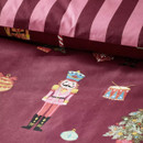 Detail of the duvet cover showing a nutcracker soldier, drum, baubles, and Christmas tree motifs on a burgundy background.