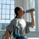 Woman drinking from Brita grey water filter bottle in bright modern interior