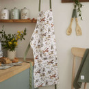 Lifestyle shot of Forest Fable apron with woodland animal print hanging in a rustic kitchen setting