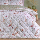 A view of a quilted Catherine Lansfield reversible bedspread showing the white side on a bed