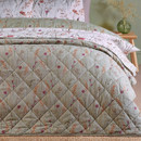 A view of a quilted Catherine Lansfield reversible bedspread showing the green side on a bed