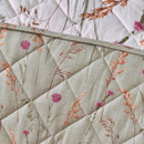 A close up view of a quilted Catherine Lansfield reversible bedspread showing the green side on a bed