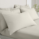 A view of a 2 pack of cream pillowcases on a bed