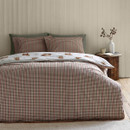 The same bedding set shown reversed, highlighting the duvet cover and pillowcases with a traditional tartan-style plaid pattern in muted green, cream, and red, with a peek of the Highland cow print on the duvet fold.