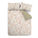 Overhead view of the bedding set with pillowcases and duvet in the white floral meadow print, with the duvet folded back to reveal the sage green reverse patterned with the same wildflowers.