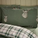 Close-up of a pillowcase featuring a large illustrated stag head on a soft green background, with the edge of the duvet showing the coordinating plaid lining in shades of green and white.
