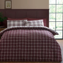 The bedding set styled with the duvet reversed, showing the darker plum-toned check pattern on top, complemented by the white-based check pillowcases.