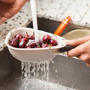 Small Joseph Joseph Nest Colander rinsing fresh cherries under running tap water.