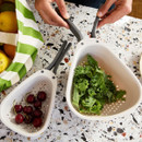 Joseph Joseph Nest Colanders in use, holding cherries and leafy kale on a kitchen counter.