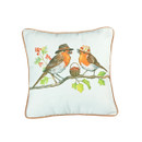 Two cartoon robins wearing hats sit on a branch, facing each other, with a basket of berries between them. The pillow background is light with a brown trim.