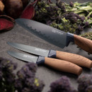Close-up of Brooklyn Walnut kitchen knife set with black non-stick blades and walnut effect handles displayed on a dark surface with vegetables.