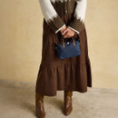 Brown skirt outfit styled with a navy mini grab bag held by the top handles.