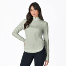 Woman wearing a light sage green long-sleeve quarter zip fleece top with curved hem, styled with black leggings.
