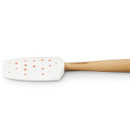 Close-up of the Le Creuset Medium Spatula, showing the white silicone head decorated with small red and pink hearts and a natural wooden handle.