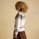 Side view of woman wearing cream and tan Fair Isle patterned jumper with blue accents, styled with a brown skirt.