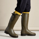 Le Chameau green wellington boots being worn, showing the tall design, adjustable calf gusset and black treaded soles.