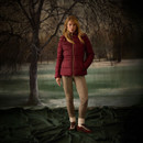 Full-length view of a woman in a burgundy padded jacket with slim-fit checked trousers and burgundy trainers.