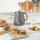 Salter grey electric kettle placed on kitchen counter beside breakfast items, featuring ribbed modern design and chrome accents — perfect stylish kettle for any home.