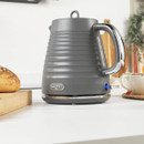 Salter grey electric kettle with ribbed body and chrome handle shown on kitchen counter, illuminated power switch and cordless base for convenient modern tea making.