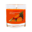 Bright orange Mediterranean Orange fragranced candle burning in a clear glass jar, with label showing ripe oranges on branches, giving a zesty, sun-drenched feel.