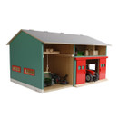 Toy barn with green walls and a grey roof, featuring two red sliding doors. Inside are miniature tractors and farming equipment, creating a playful farm scene.