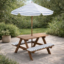 A view of a wooden children's bench with matching blue and white striped cushions and parasol in a garden