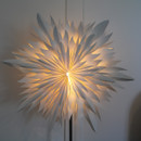 A close up view of a prelit paper snowflake decoration on a silver stand.