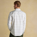 A person with light hair is standing with their back to the camera, wearing a white Joules checkered shirt and green pants. The background is a beige wall.