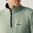 A close up front view of a man wearing a light sage Regatta fleece on a white background