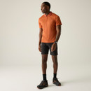 A front view of a man wearing an orange Regatta polo shirt on a white background