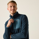 A close up view of a man wearing a navy full zip fleece on a white background